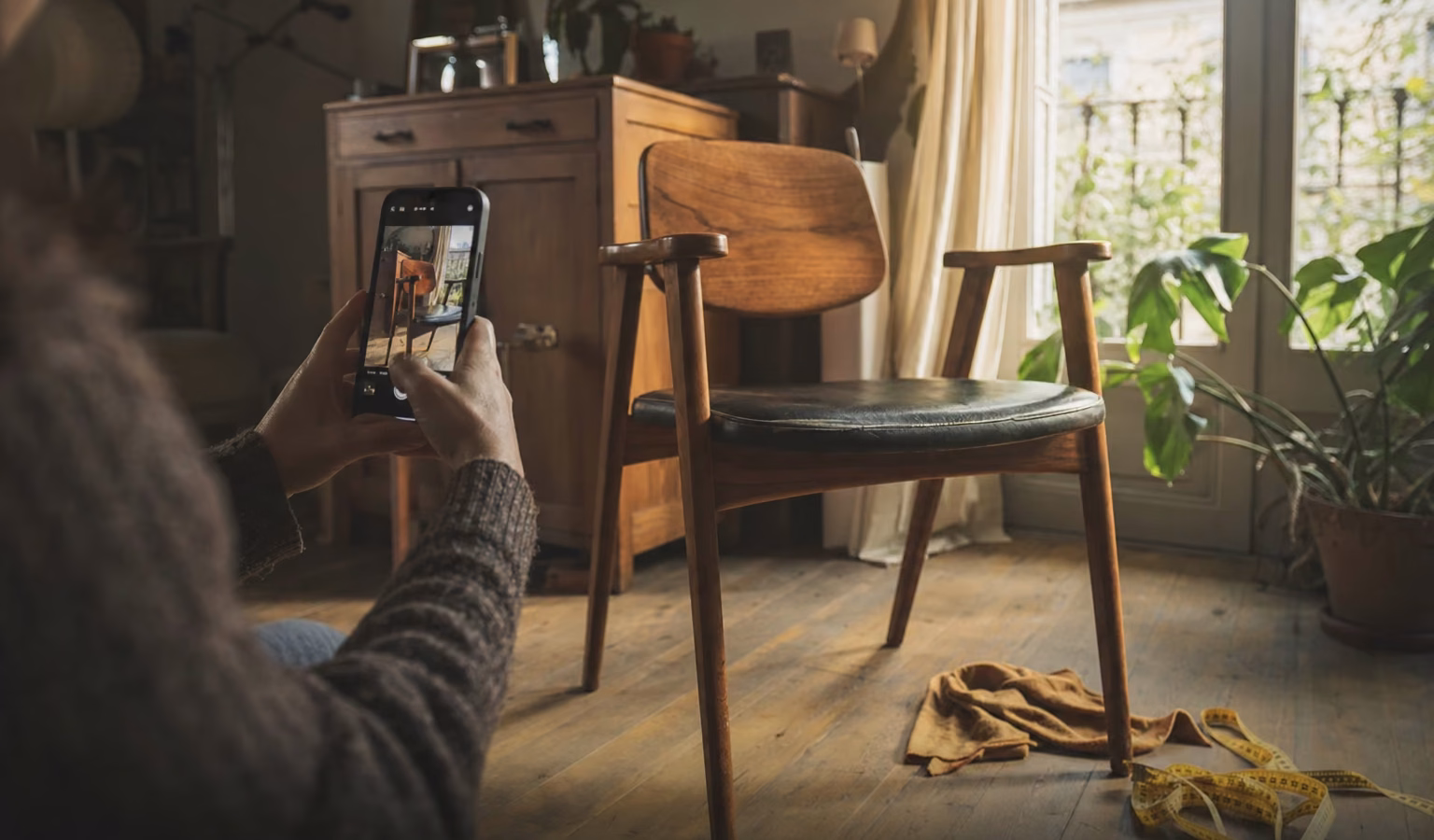 Manos fotografiando con el móvil una silla de madera para venderla de segunda mano